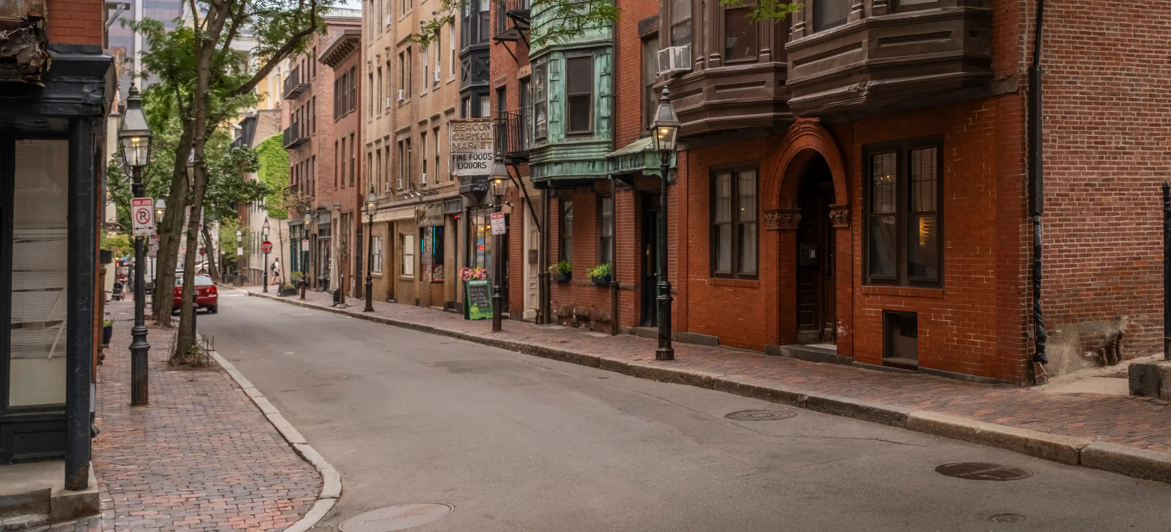 A row of brick storefronts on a Boston side street at dusk